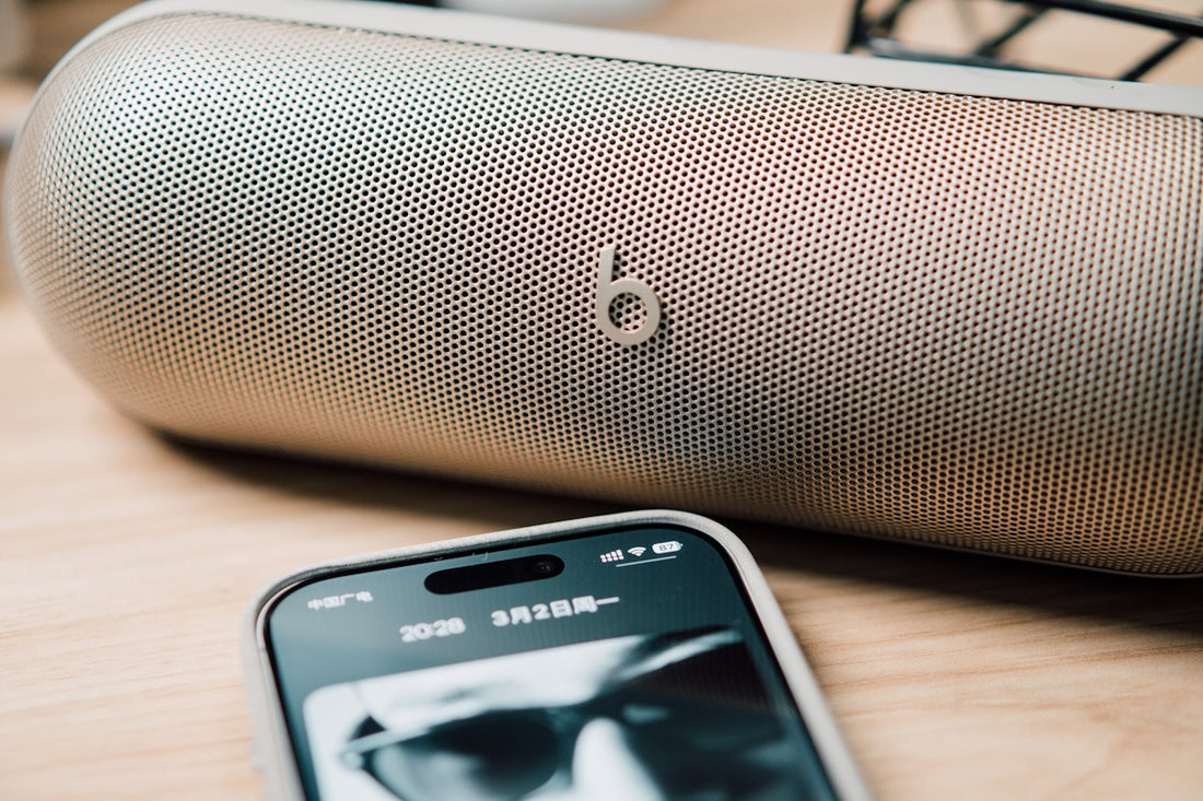 A portable speaker and smartphone on a wooden surface