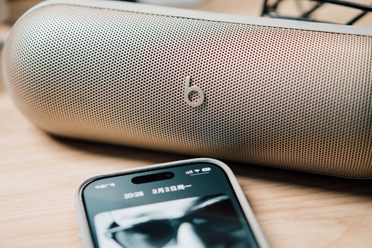A portable speaker and smartphone on a wooden surface