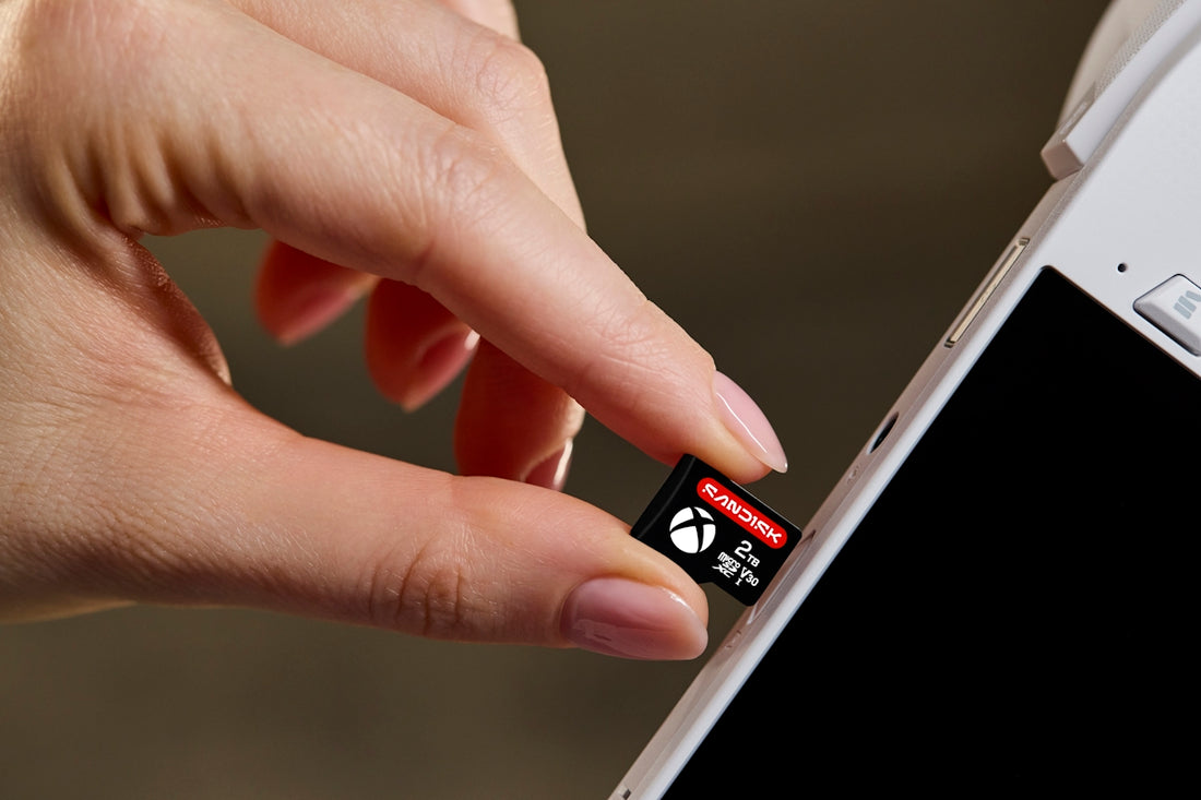 Hand inserting a memory card into a white electronic device.